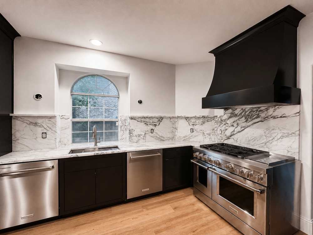 Custom kitchen - marble, black cabinetry, double ovens